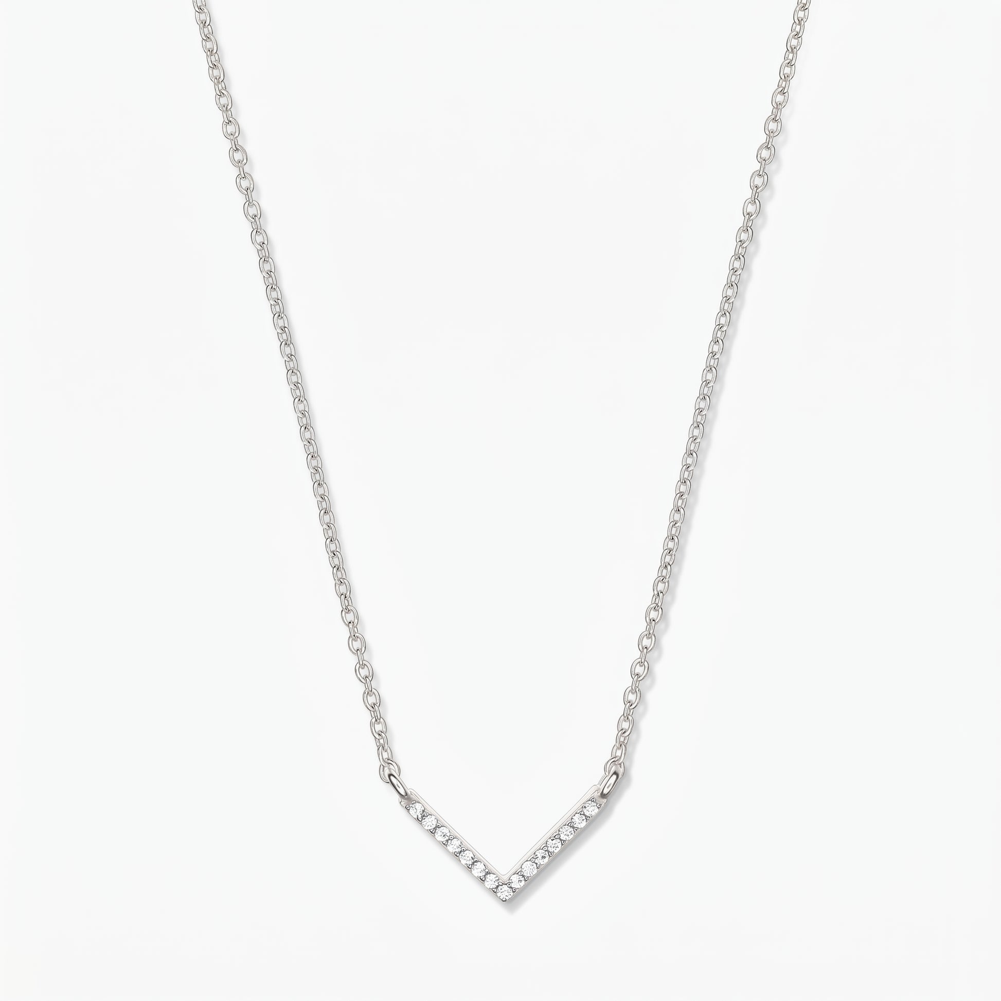 Collier en argent en forme de V avec chaîne délicate et pendentif chevron pavé d’oxydes de zirconium, sur fond blanc.