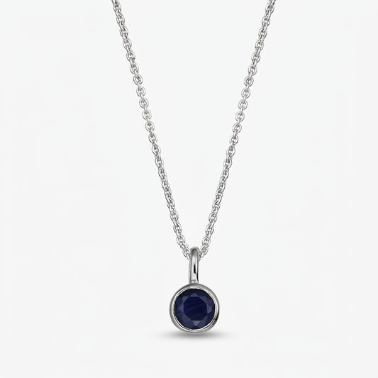 Collier en argent sterling avec pierre de naissance, pendentif rond en saphir bleu foncé serti clos sur une chaîne fine, isolé sur fond blanc.