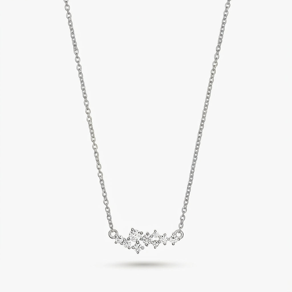 Collier constellation délicat en argent avec de petites pierres transparentes sur une fine chaîne, isolé sur fond blanc.