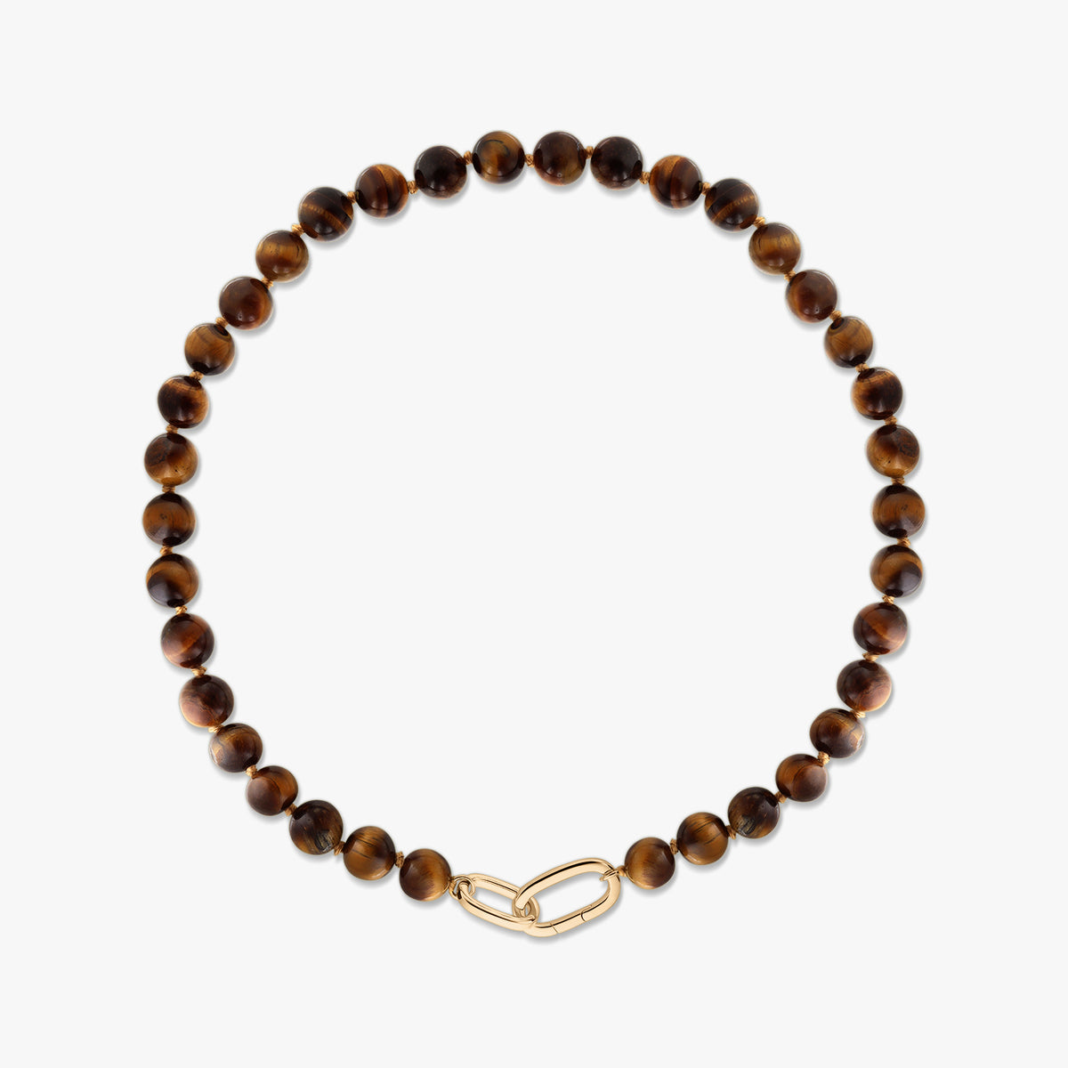 Collier à perles en œil de tigre avec pierres rondes polies marron doré et fermoir en argent plaqué or style trombone sur fond blanc.
