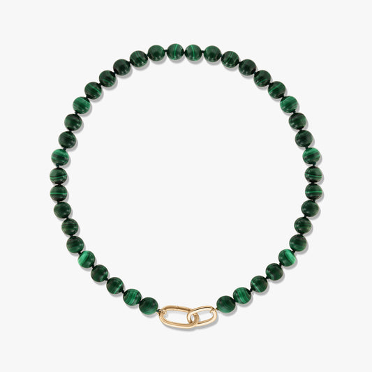 Collier en perles de malachite verte avec fermoir en argent sterling plaqué or en forme d’agrafe, sur fond blanc.