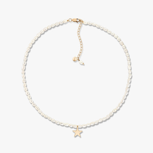 Collier délicat de perles de culture avec un petit pendentif étoile en or et un allongeur réglable en or, présenté sur fond blanc.