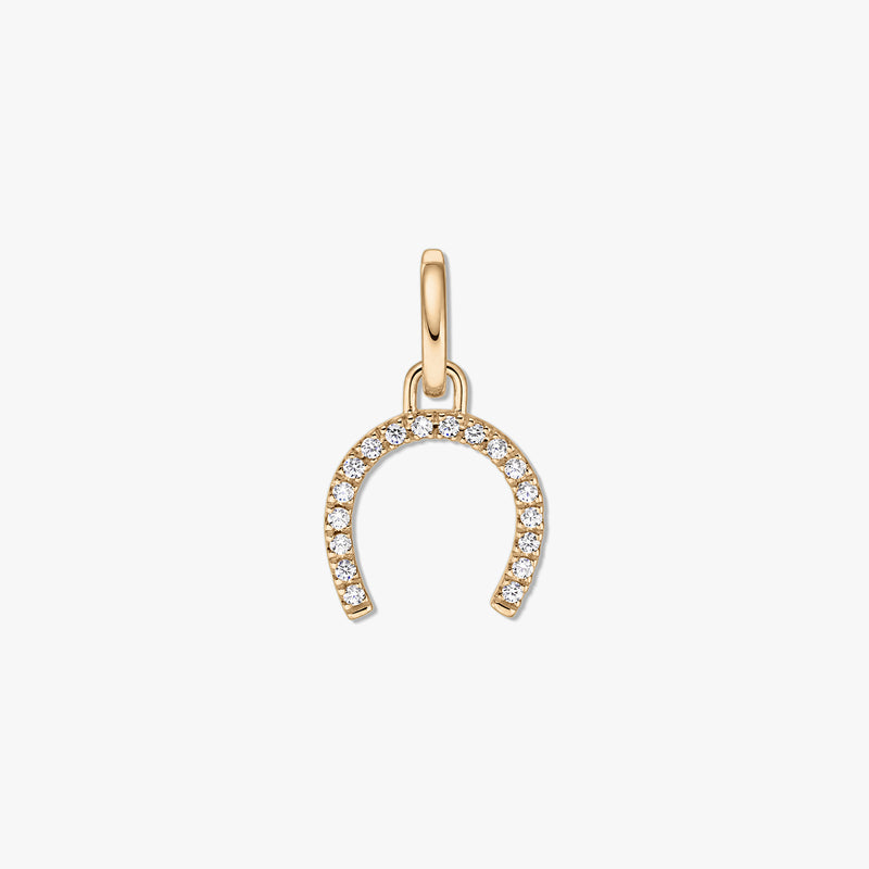 Pendentif fer à cheval en argent doré serti de pierres de zirconium claires sur fond blanc.