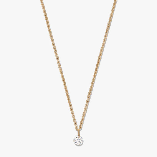 Collier en argent doré avec pendentif solitaire rond en oxyde de zirconium clair, sur fond blanc.