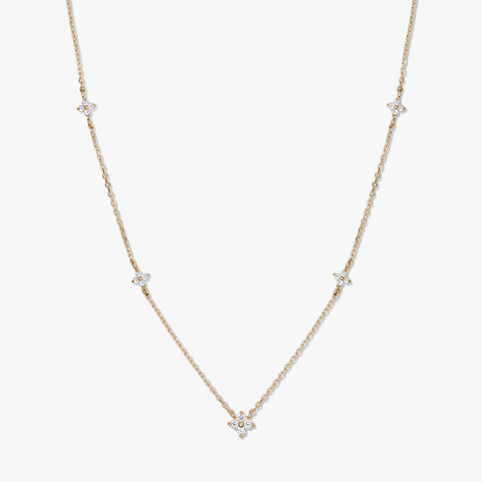 Collier délicat en or jaune 14K de type station, avec de petits motifs trèfle en zirconia blanc sur une chaîne fine, photographié sur fond blanc.