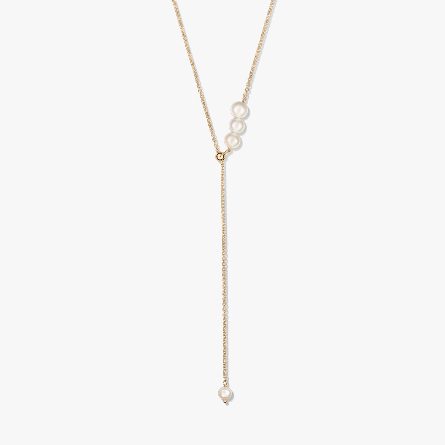 Collier lariat délicat en argent sterling plaqué or, avec un trio de perles de culture au curseur et une perle pendante unique, sur fond blanc.