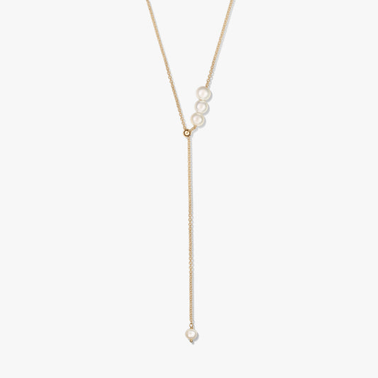 Collier lariat délicat en argent sterling plaqué or, avec un trio de perles de culture au curseur et une perle pendante unique, sur fond blanc.