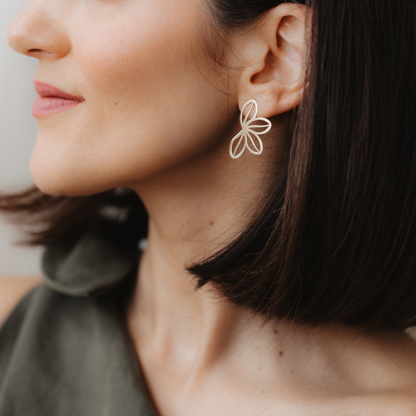 Gros plan d’un mannequin portant la boucle d’oreille à clou Half Wildflower en or jaune 14K au design à pétales ouverts. Lumière intérieure douce et arrière-plan neutre.