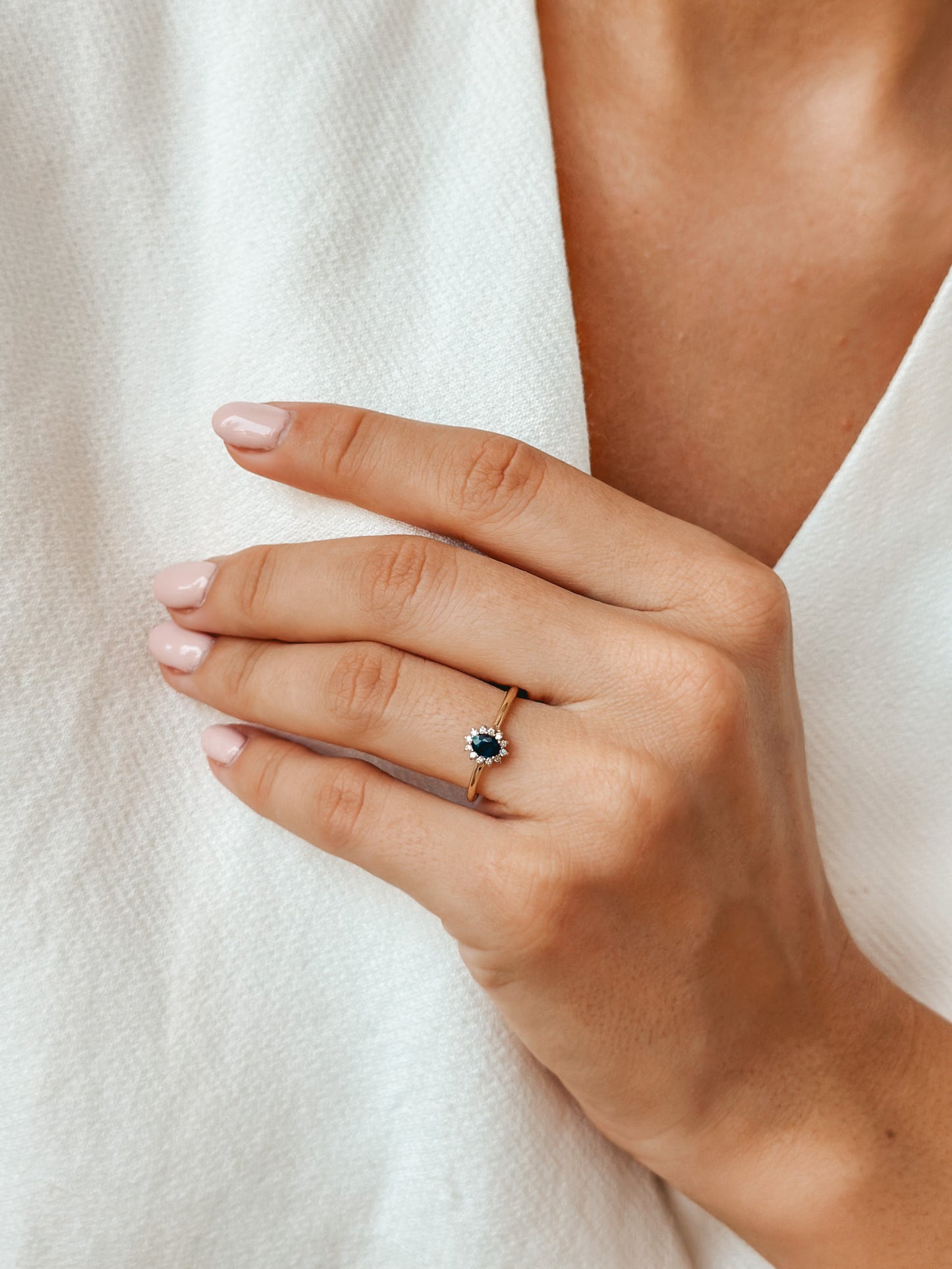 Gros plan d'une main portant une bague en or avec un saphir et des diamants