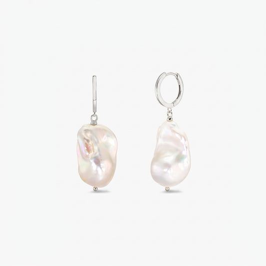 Paire de créoles en argent sterling avec de grandes perles baroques blanches, irrégulières, sur fond blanc uni.