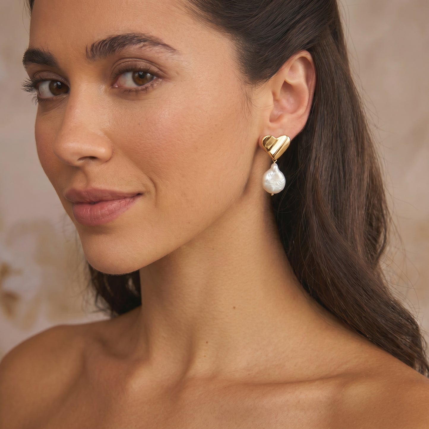 Gros plan d'une femme portant une boucle d'oreille en argent plaqué or en forme de cœur avec une pierre naturelle en forme de poire suspendue.