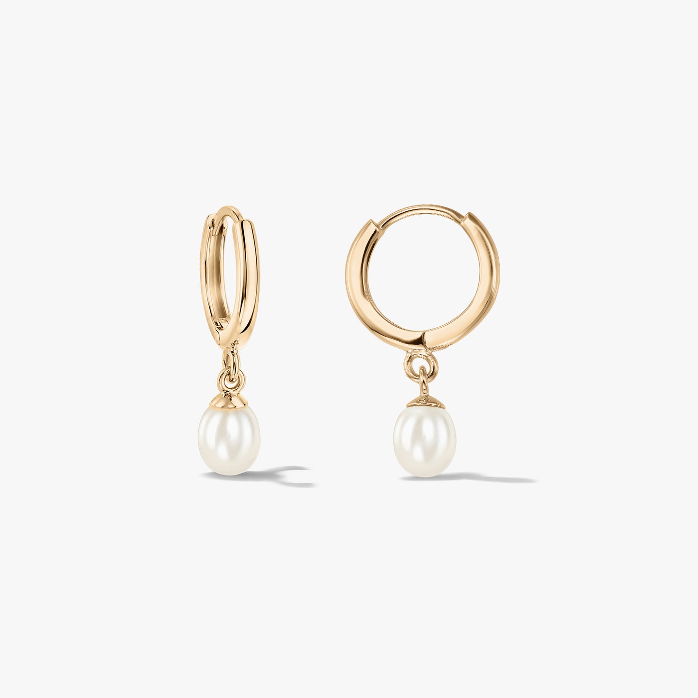 Paire de créoles élégantes en or jaune 14K ornées de perles naturelles, sur fond blanc.