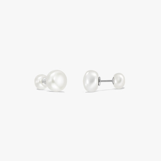 Paire de boucles d’oreilles puces à double perle en argent sterling sur fond blanc, chacune avec une grande perle naturelle blanche à une extrémité et une plus petite à l’autre, reliées par une tige.