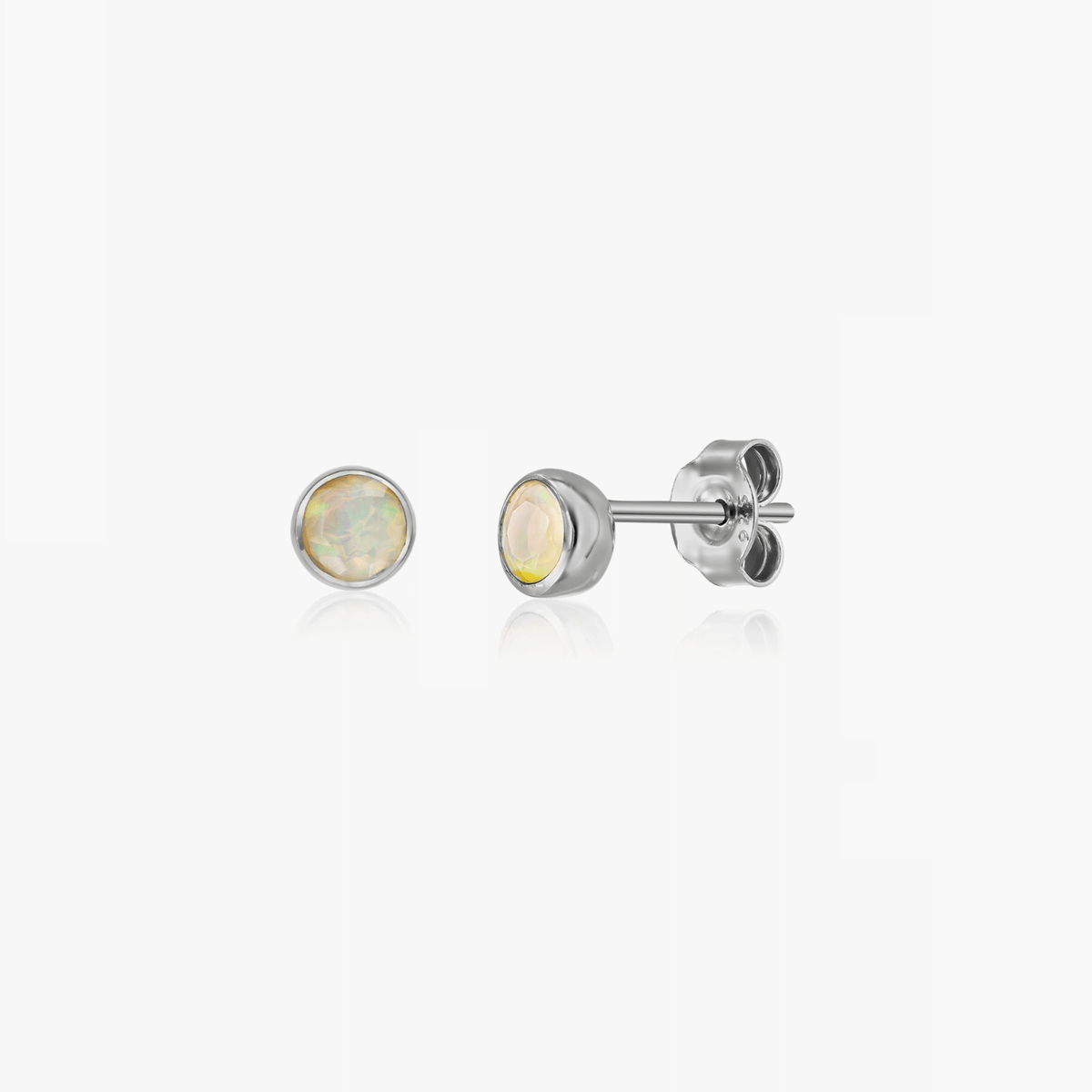 Une paire de boucles d'oreilles en argent avec pierre d'opale, conçues comme des clous de naissance pour le mois d'octobre.