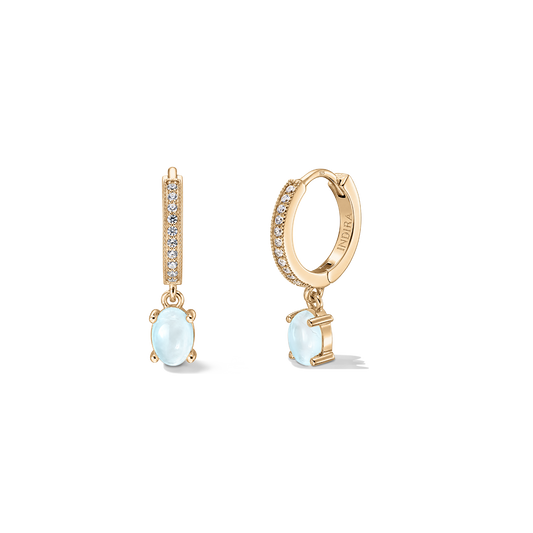 Paire de boucles d'oreilles créoles huggie en argent 925 doré avec détails pavé et gouttes ovales en pierre de lune sur fond blanc.