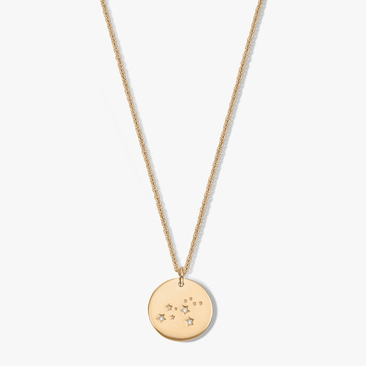 Golden Zodiac – Collier pendentif disque rond Leo, orné de petites étoiles et de points sertis de saphirs blancs sur une chaîne délicate, isolé sur fond blanc.
