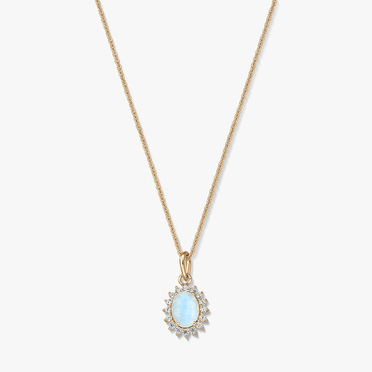 Collier en argent sterling plaqué or avec pendentif ovale en pierre de lune bleu clair, encadré de petites pierres transparentes, sur fond blanc.