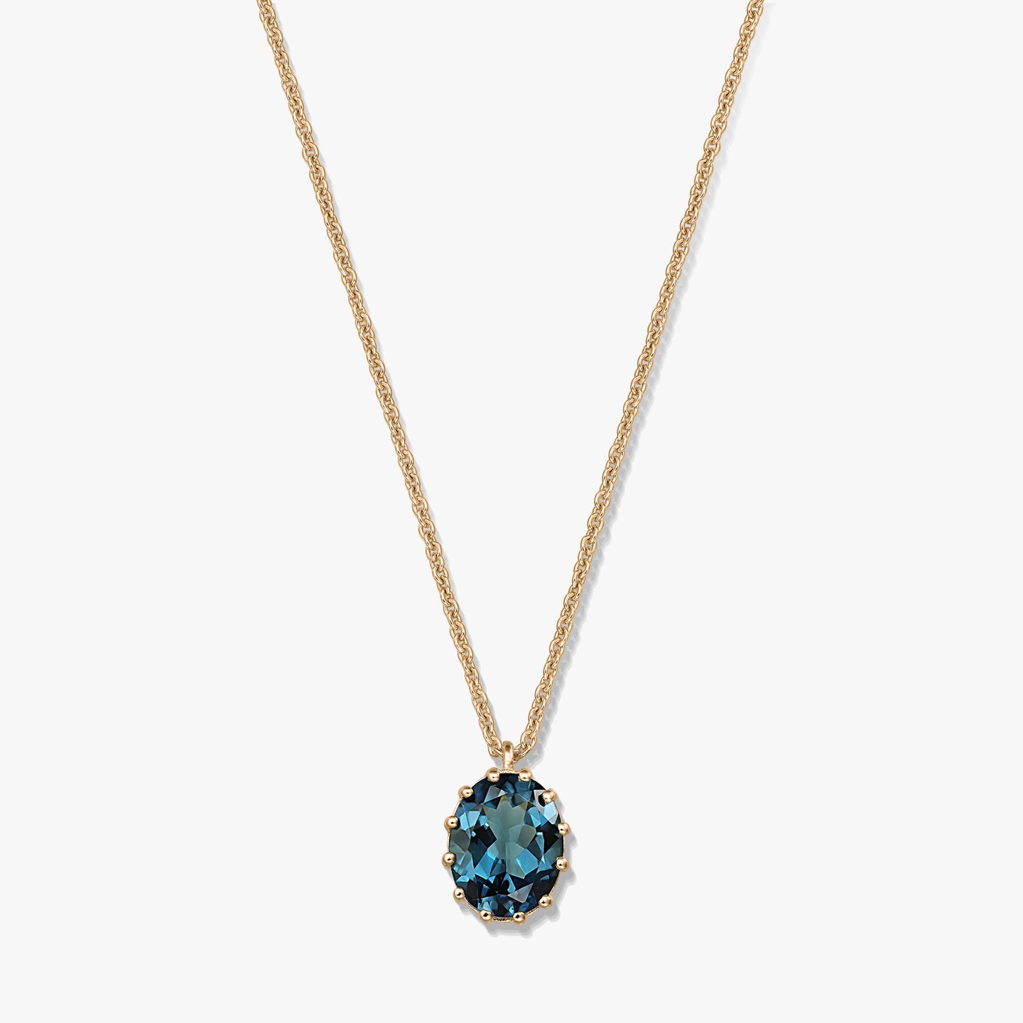 Collier en argent sterling plaqué or avec pendentif ovale en topaze bleu London, sur fond blanc.