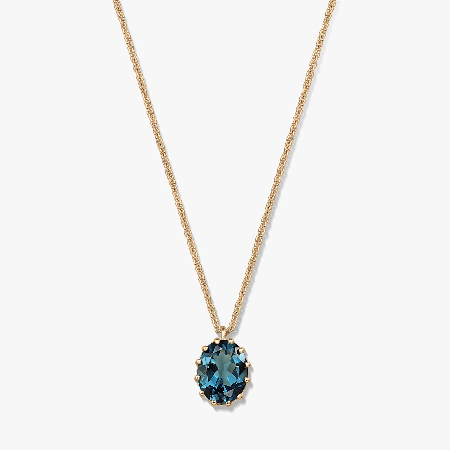 Collier en argent sterling plaqué or avec pendentif ovale en topaze bleu London, sur fond blanc.