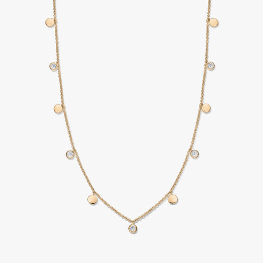 Collier à stations en argent sterling plaqué or avec de petits disques polis alternés et des topazes blanches en serti clos sur une chaîne délicate, photographié sur fond blanc.