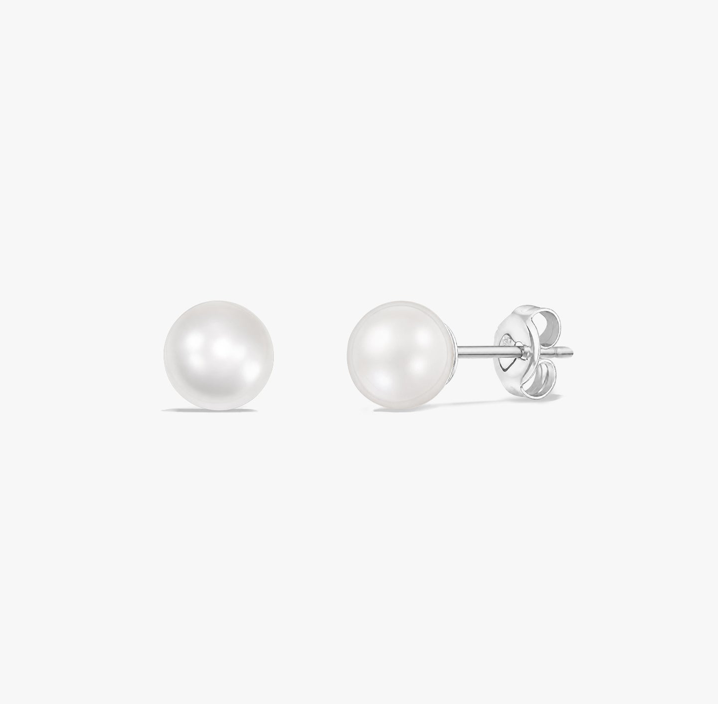Paire de puces d’oreilles élégantes en perles blanches naturelles serties en argent sterling 925 sur fond blanc.