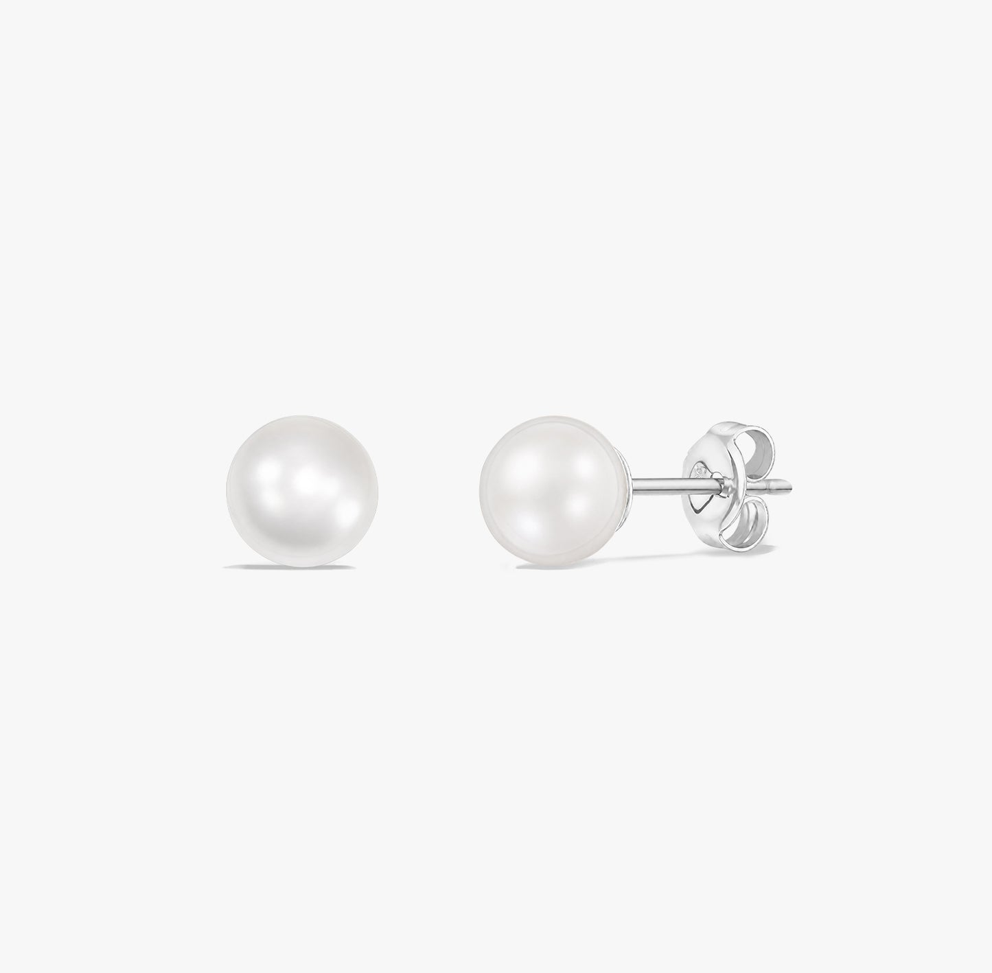 Paire de puces d’oreilles élégantes en perles blanches naturelles serties en argent sterling 925 sur fond blanc.
