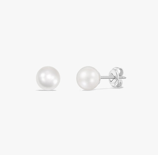 Paire de puces d’oreilles élégantes en perles blanches naturelles serties en argent sterling 925 sur fond blanc.