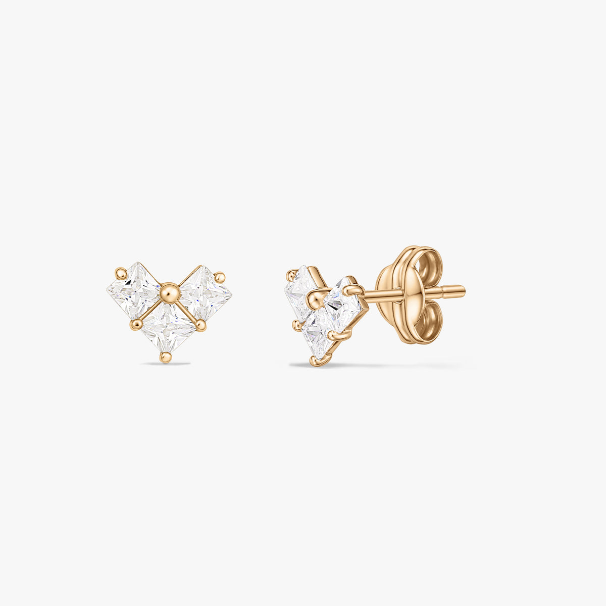 Paire de boucles d'oreilles clous en or jaune avec trois pierres carrées transparentes formant un petit groupe en forme de cœur, présentées sur fond blanc.