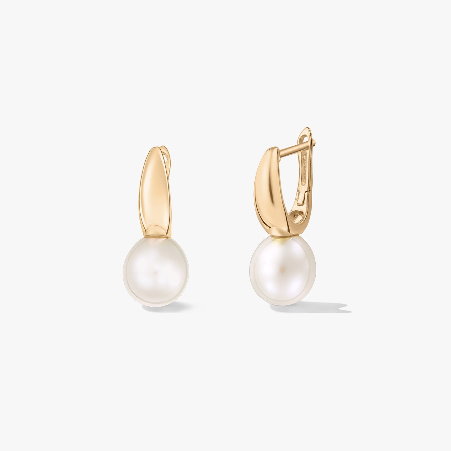 Photo produit en studio de boucles d’oreilles dormeuses en argent plaqué or avec des perles naturelles blanches rondes sur fond blanc ; une boucle d’oreille est ouverte pour montrer le fermoir.