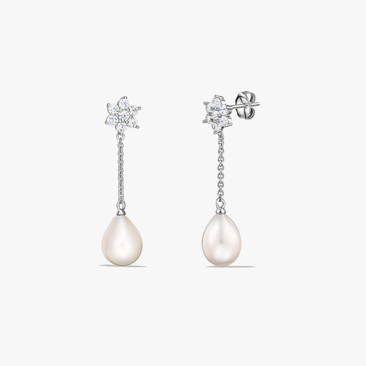 Paire de boucles d’oreilles pendantes en argent sterling avec des perles de culture en forme de goutte suspendues à une courte chaîne et un petit motif scintillant au niveau du clou, sur fond blanc.