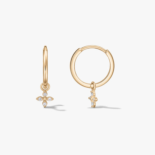 Paire de créoles en or jaune 14K ornées de petits pendentifs fleur à quatre pétales sertis d’oxydes de zirconium, sur fond blanc.