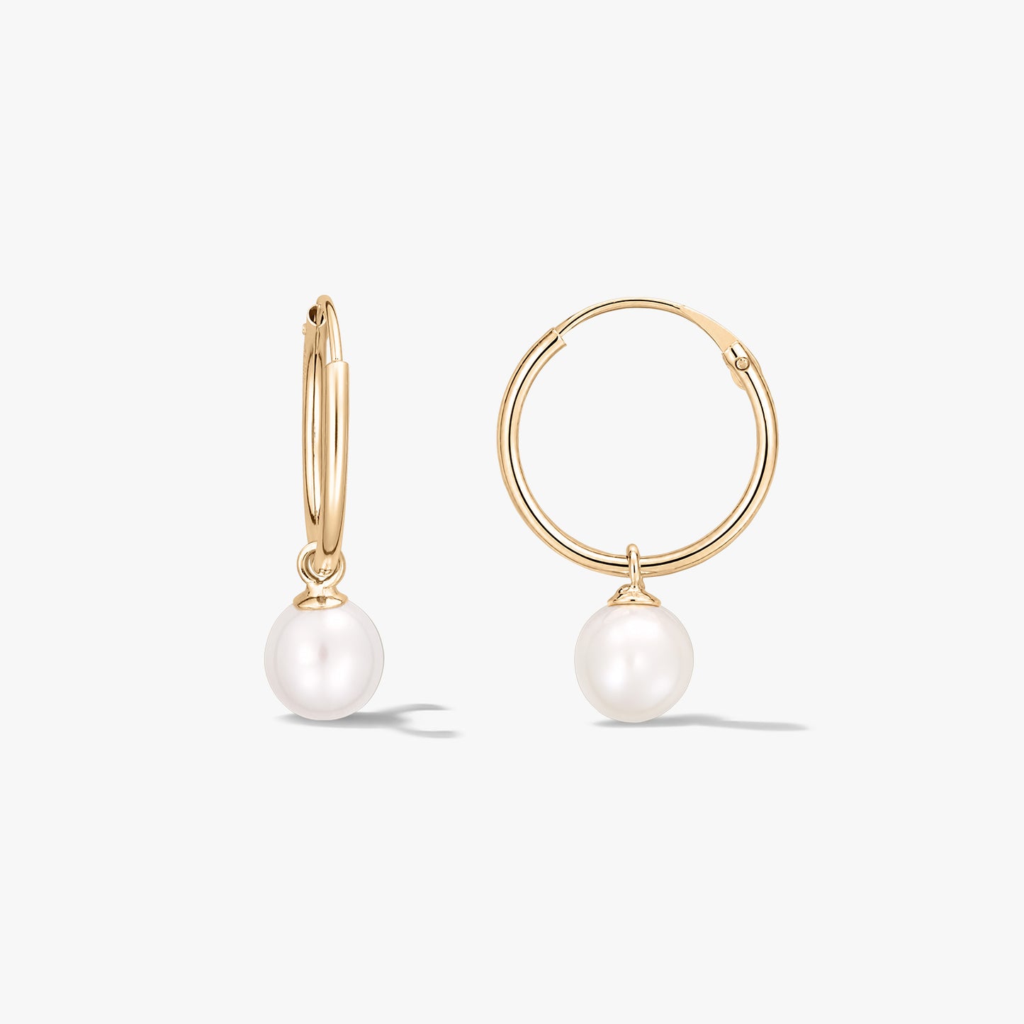 Paire de boucles d’oreilles créoles en or jaune ornées de perles blanches naturelles rondes, sur fond blanc.