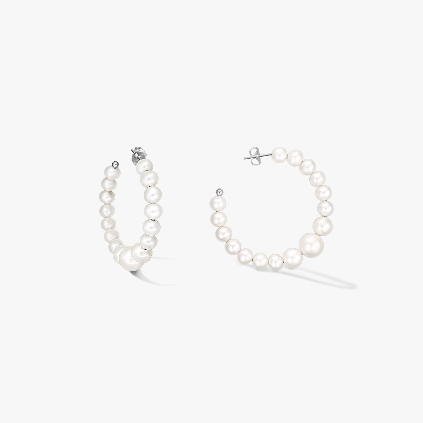 Paire de créoles en argent sterling ornées de perles blanches naturelles graduées, présentées sur fond blanc.