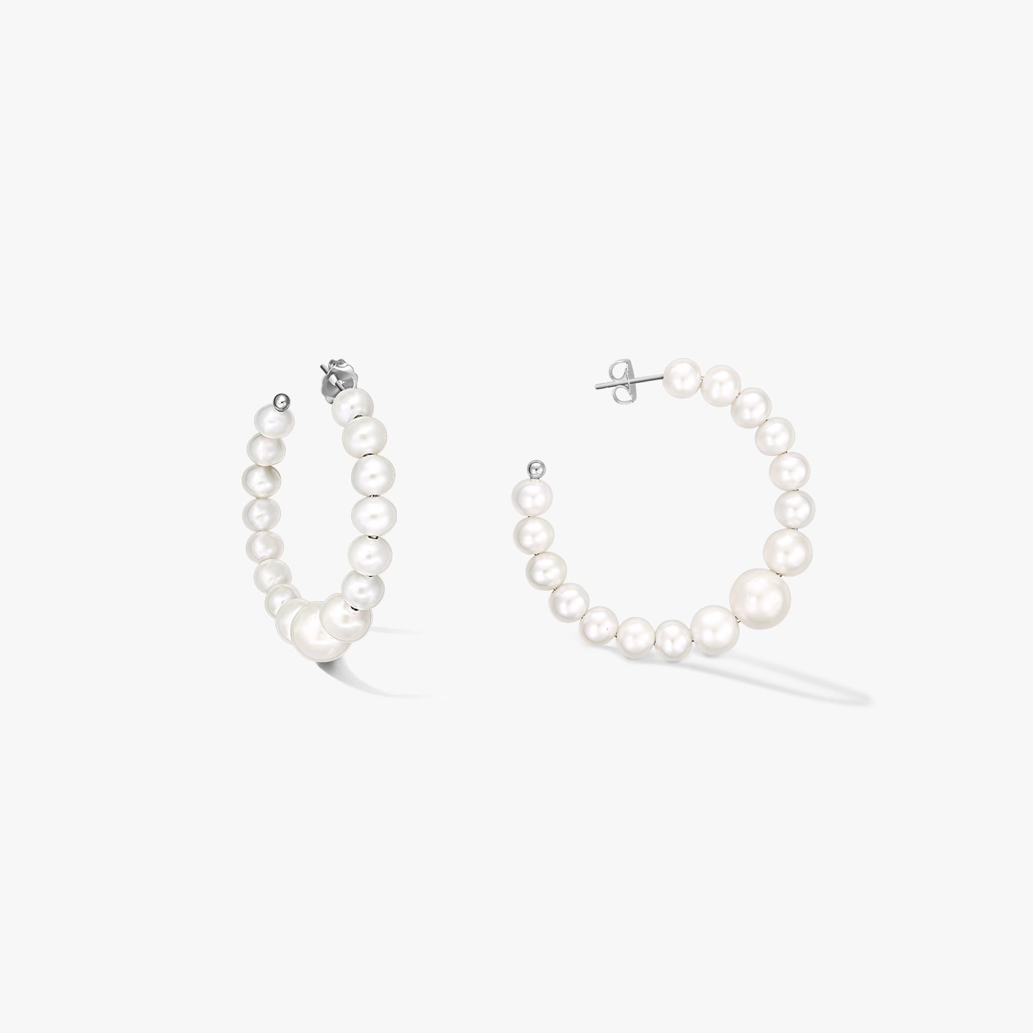 Paire de créoles en argent sterling ornées de perles blanches naturelles graduées, présentées sur fond blanc.