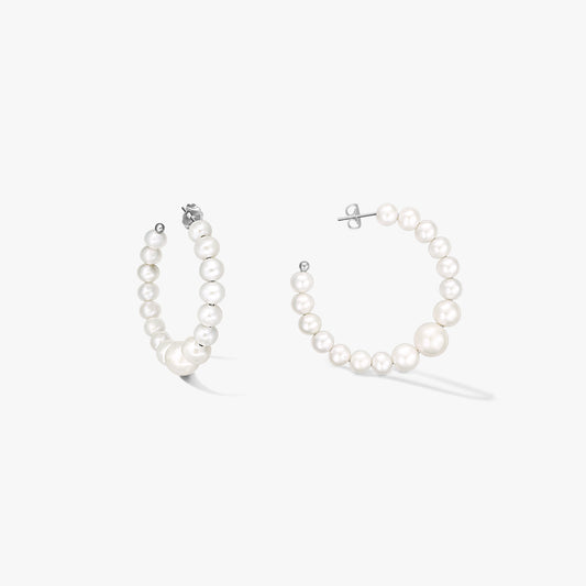 Paire de créoles en argent sterling ornées de perles blanches naturelles graduées, présentées sur fond blanc.