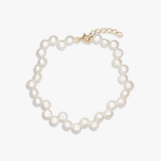 Bracelet en argent 925 plaqué or, orné de perles blanches naturelles et doté d'une chaînette d'extension réglable, photographié sur fond blanc.