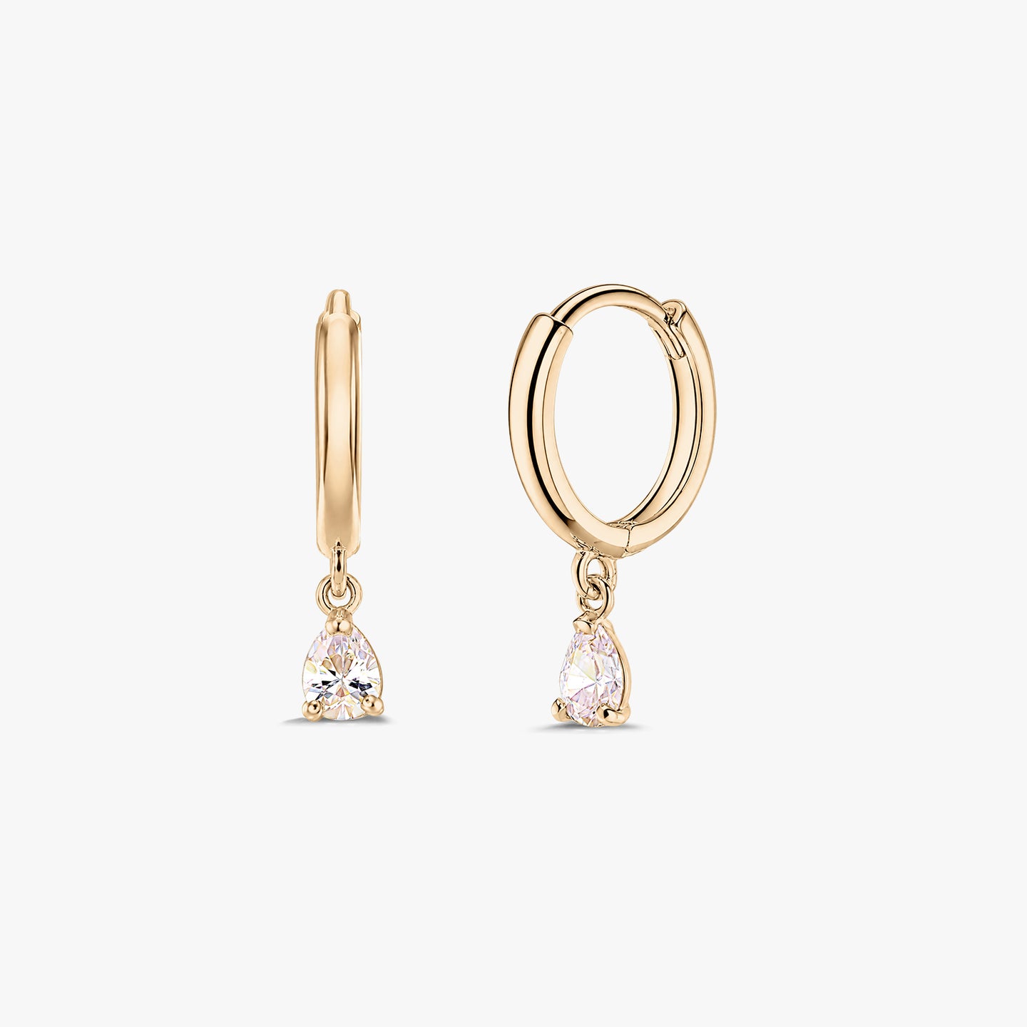 Paire de boucles d’oreilles créoles huggie en or jaune 14K avec pampilles en zircone blanche taille poire, sur fond blanc.