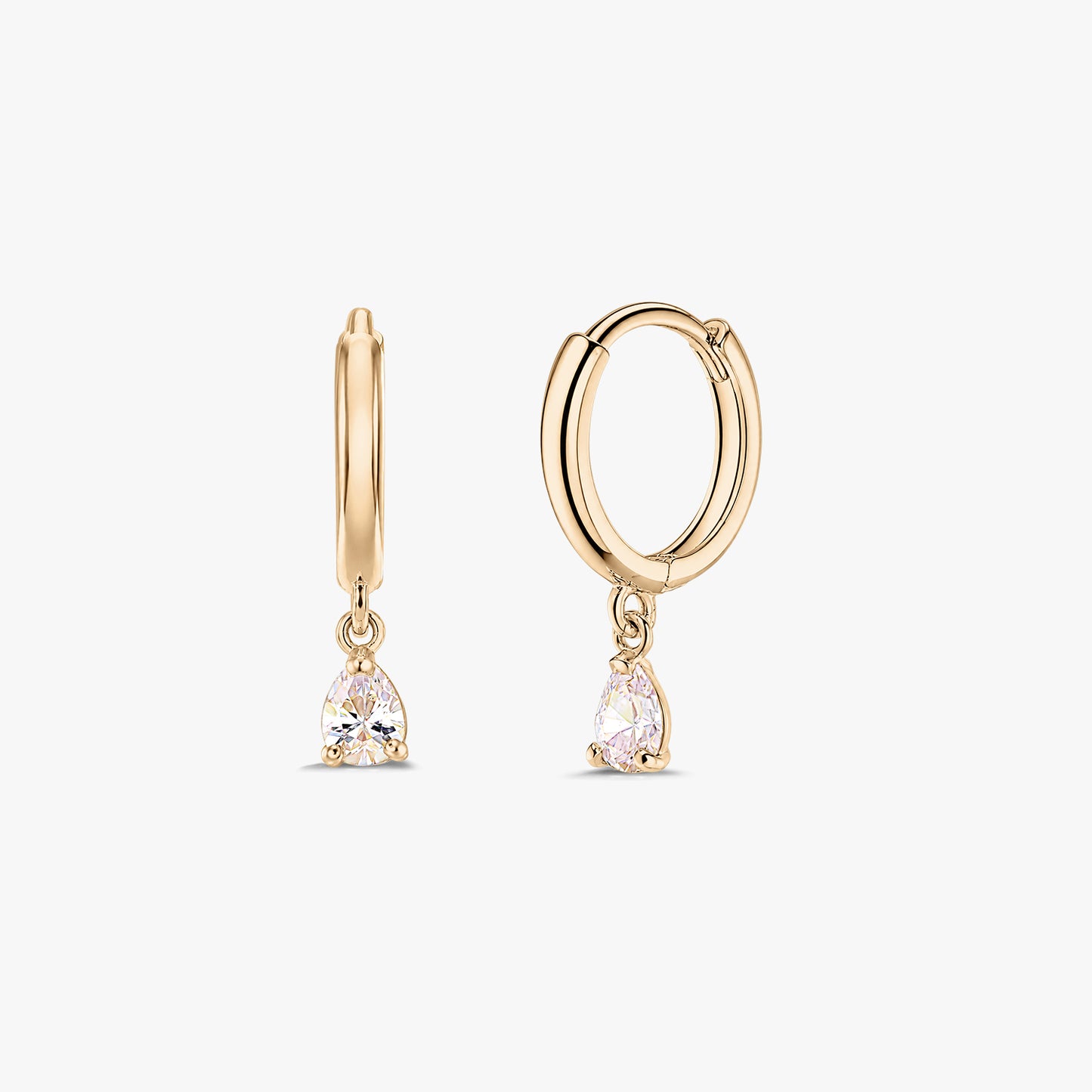 Paire de boucles d’oreilles créoles huggie en or jaune 14K avec pampilles en zircone blanche taille poire, sur fond blanc.