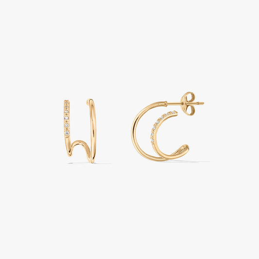 Paire de boucles d'oreilles à double anneau en or avec pierres incrustées sur fond blanc.