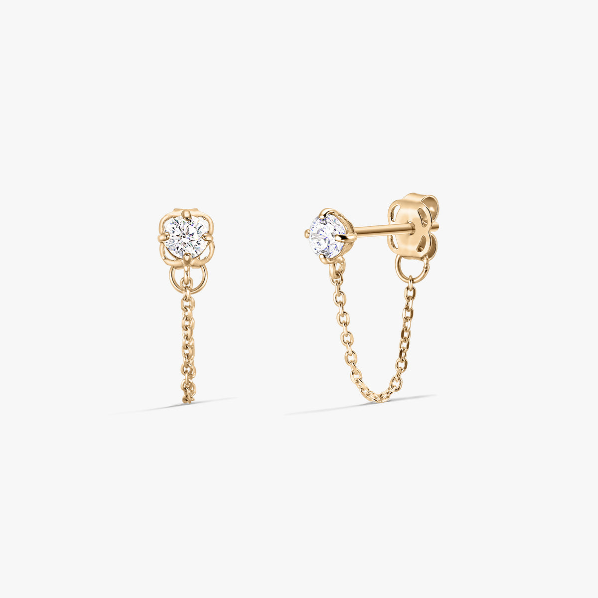 Paire de boucles d'oreilles clous Emma en or avec pierres de zirconium claires et fines chaînes pendantes, vues de face et de côté sur fond blanc.