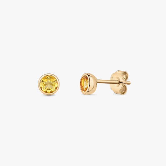 Paire de puces d’oreilles en argent ornées de pierres de naissance en citrine rondes en serti clos, sur fond blanc, vues de face et de profil avec fermoirs papillon.