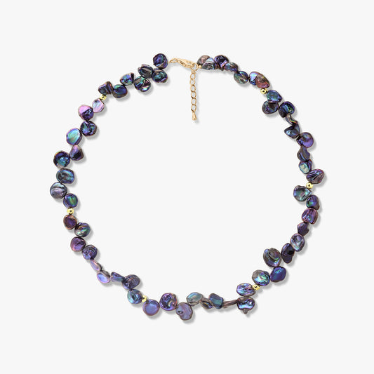 Collier de perles keshi noires irisées avec de petites touches dorées et une chaîne de rallonge réglable, photographié sur fond blanc.
