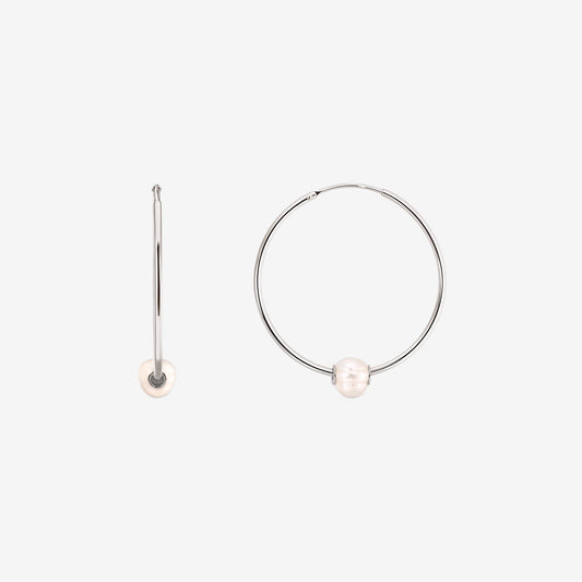 Paire de boucles d'oreilles créoles en argent sterling avec une perle blanche de culture sur chacune, présentées sur fond blanc avec une boucle vue de face et l'autre de profil.