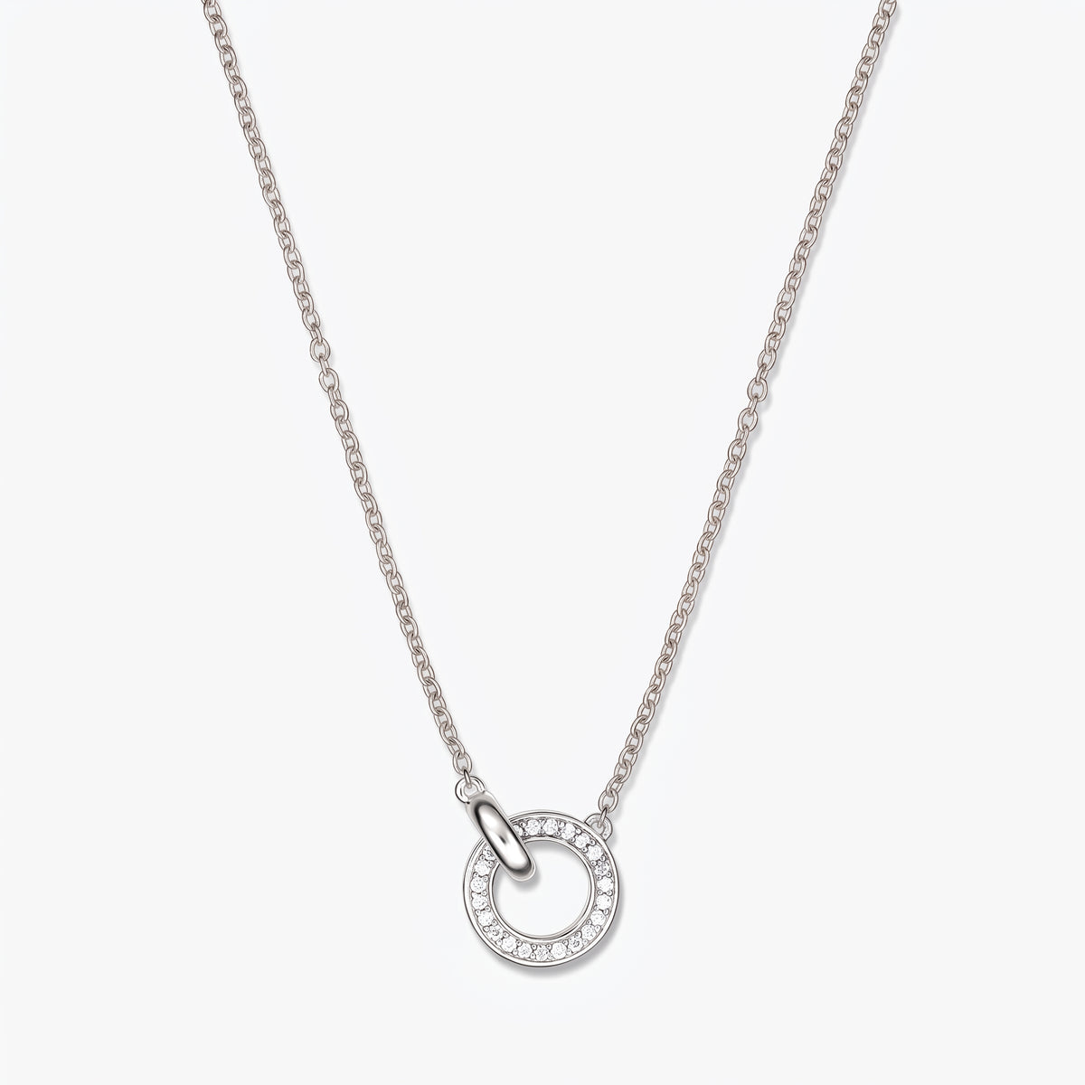 Collier en argent à maillons avec pendentif à double cercle orné de petites pierres claires, sur une fine chaîne en argent, photographié sur fond blanc.