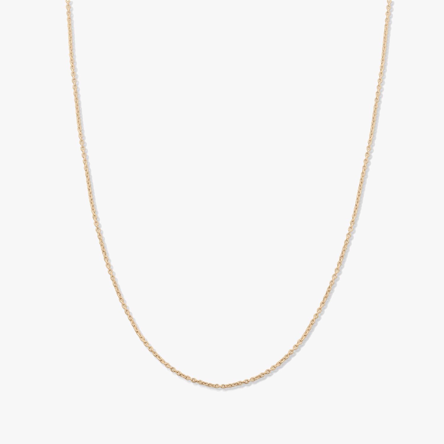 Collier chaîne en or jaune délicat à maillons fins, présenté sur fond blanc, sans pendentif.