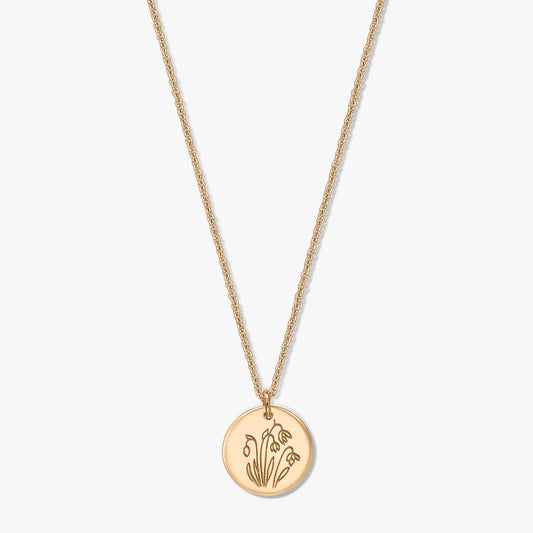 Collier en argent sterling plaqué or avec un pendentif disque rond gravé du perce-neige, fleur de naissance de janvier, présenté sur fond blanc.
