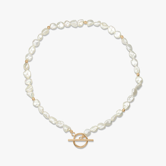 Collier en argent avec perles naturelles et fermoir toggle en or présenté sur fond blanc.