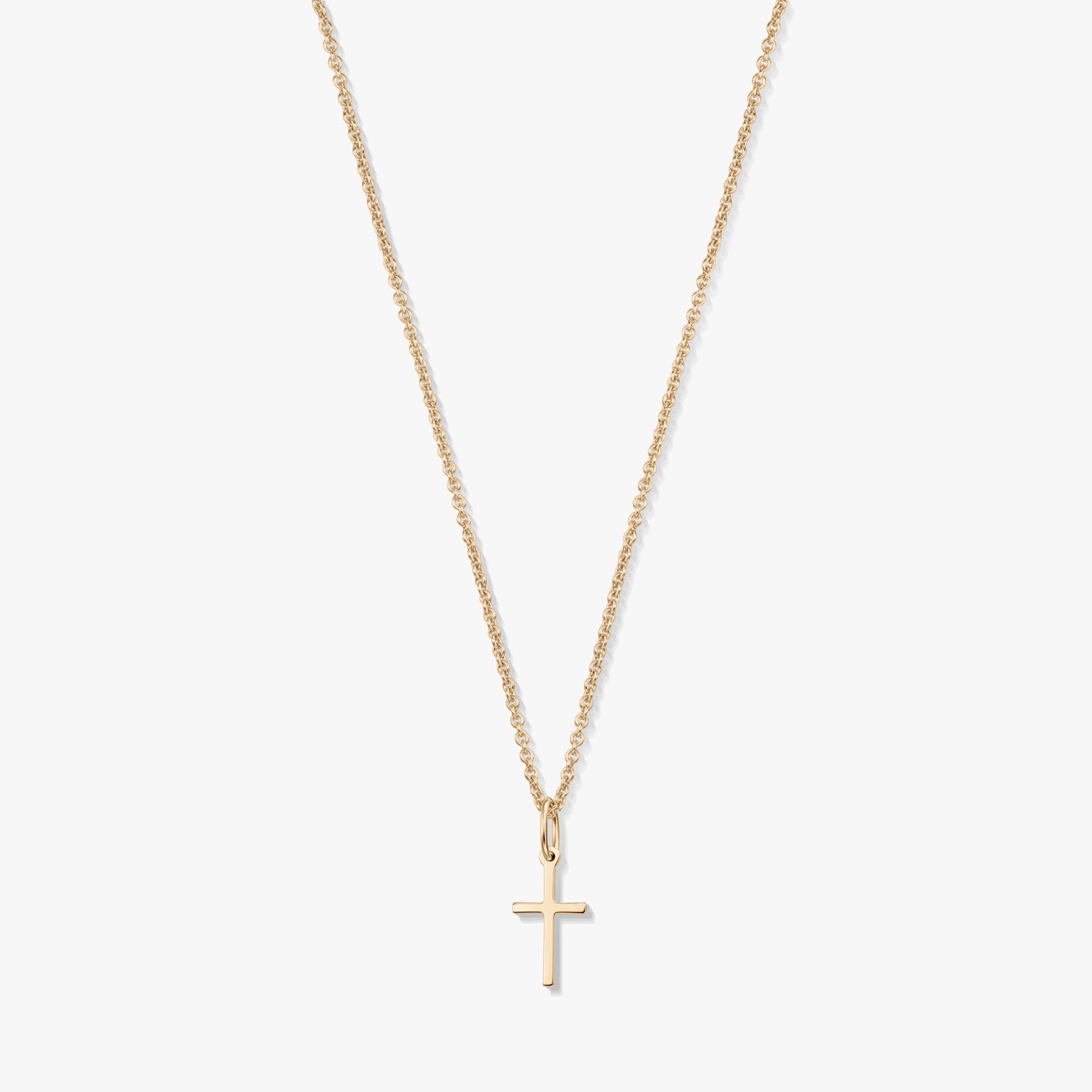 Collier minimaliste en or jaune 14K avec un petit pendentif en forme de croix sur une fine chaîne, isolé sur fond blanc.
