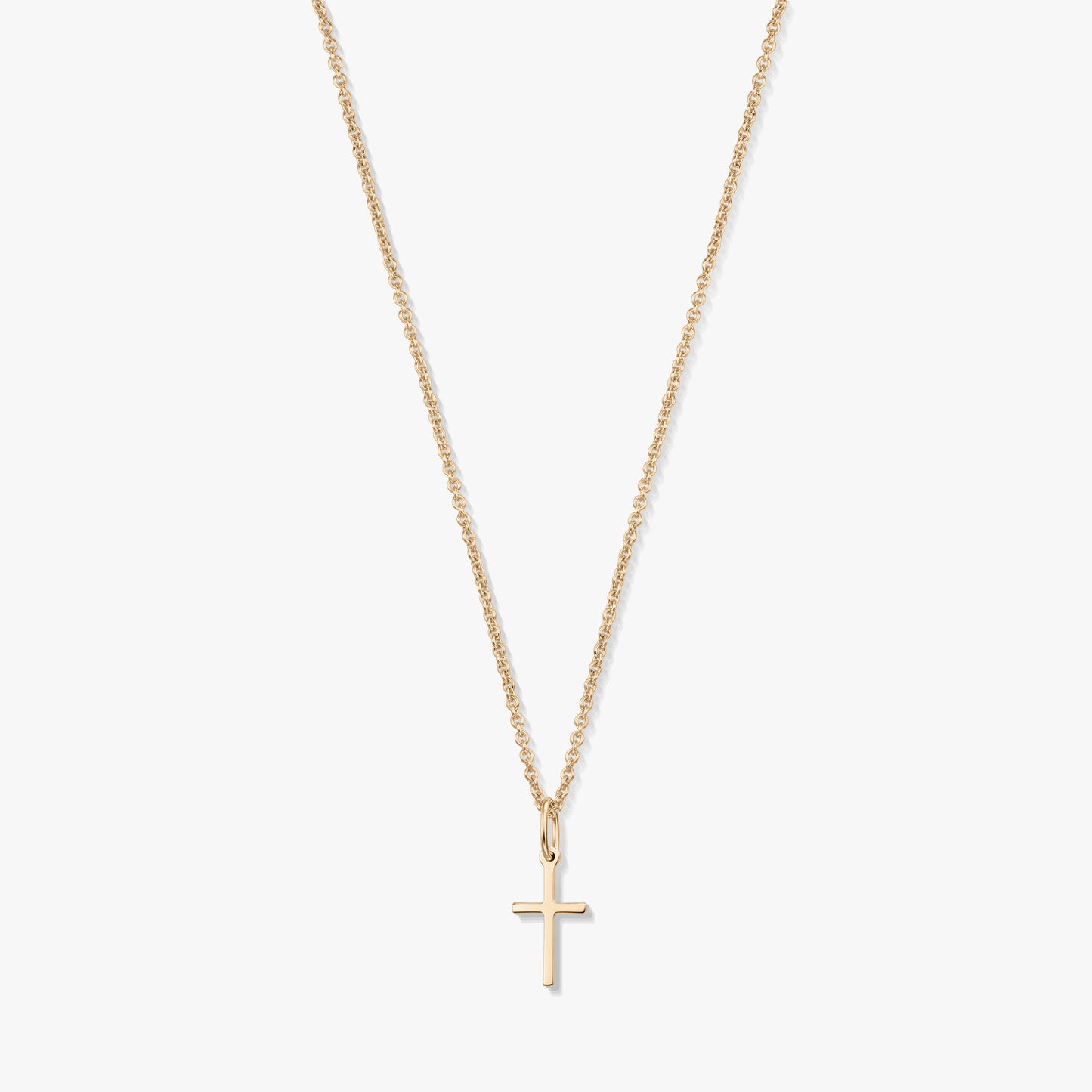 Collier minimaliste en or jaune 14K avec un petit pendentif en forme de croix sur une fine chaîne, isolé sur fond blanc.