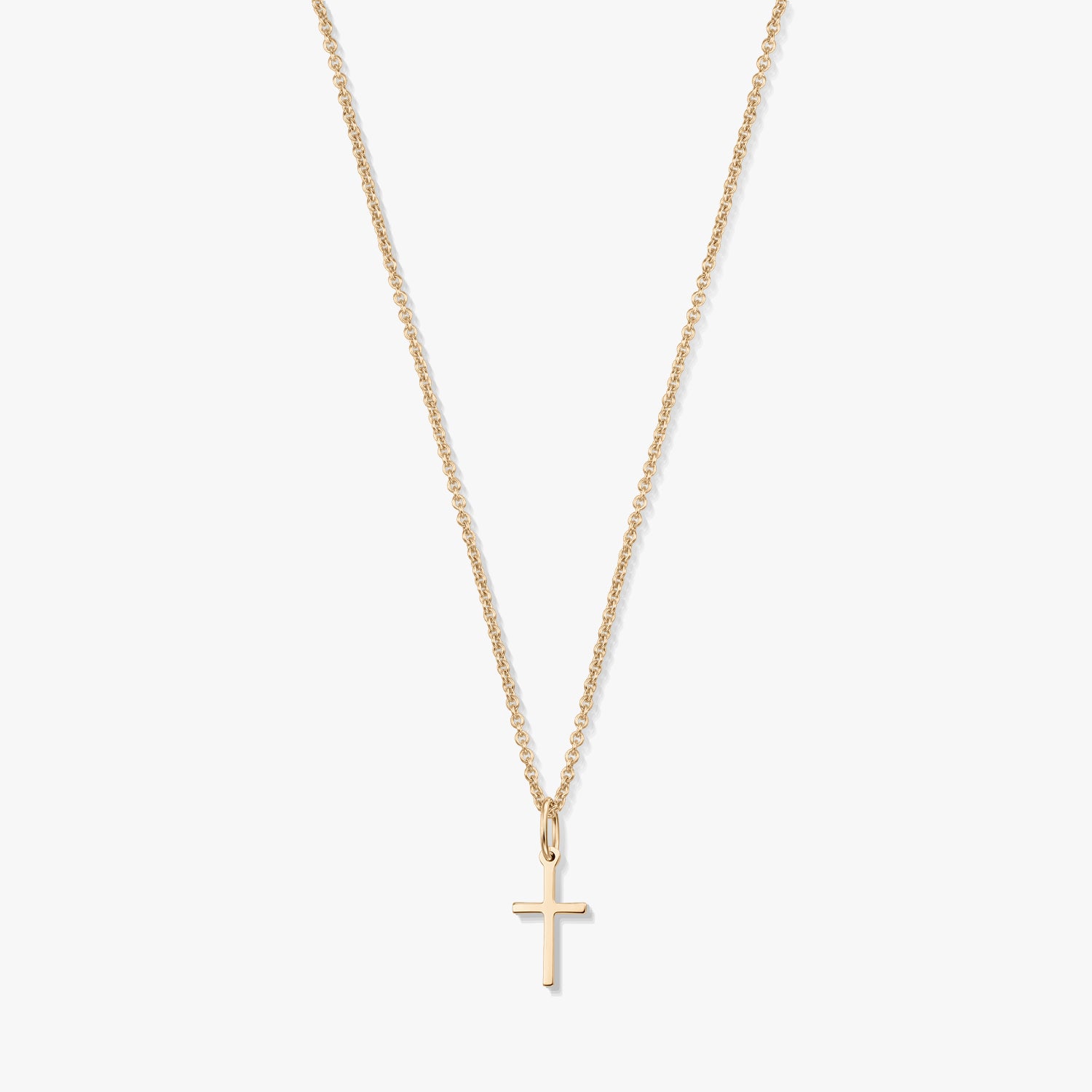 Collier minimaliste en or jaune 14K avec un petit pendentif en forme de croix sur une fine chaîne, isolé sur fond blanc.